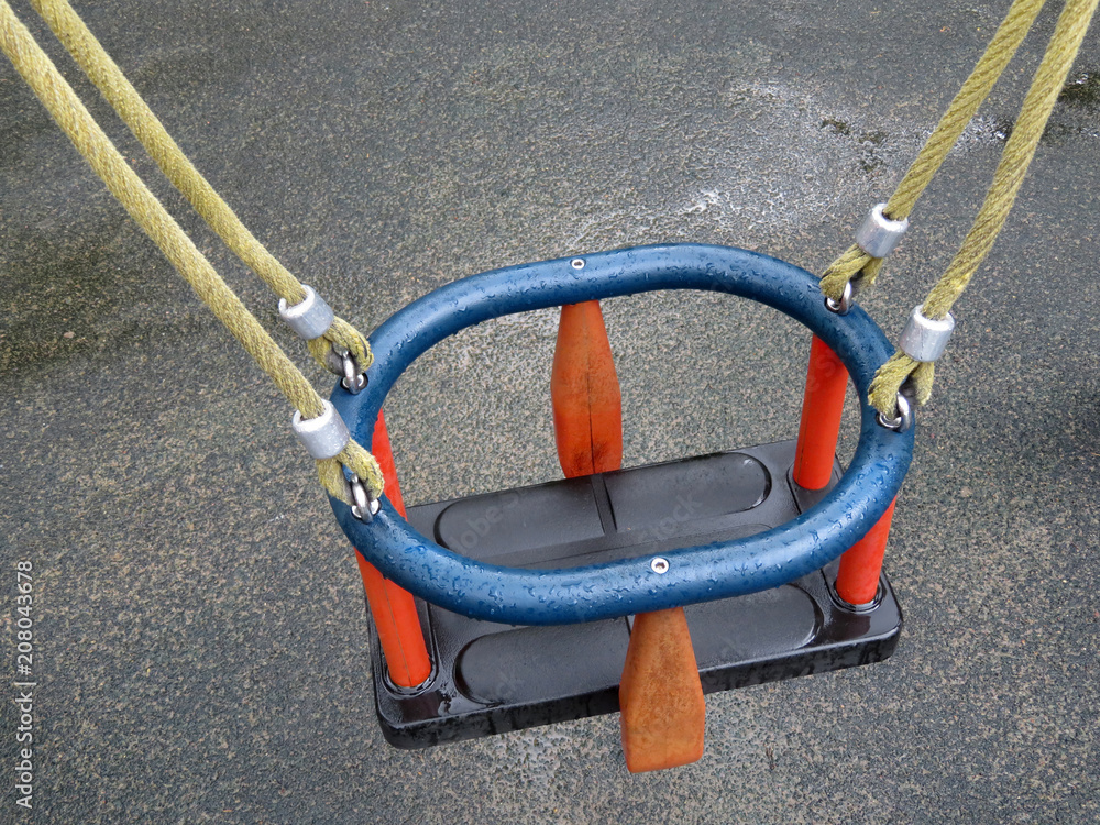 Children swing seat with water drops on the playground after rain. Missing child, abandoned kids playground Children swing seat with water drops on the playground after rain. Missing child, abandoned kids playground