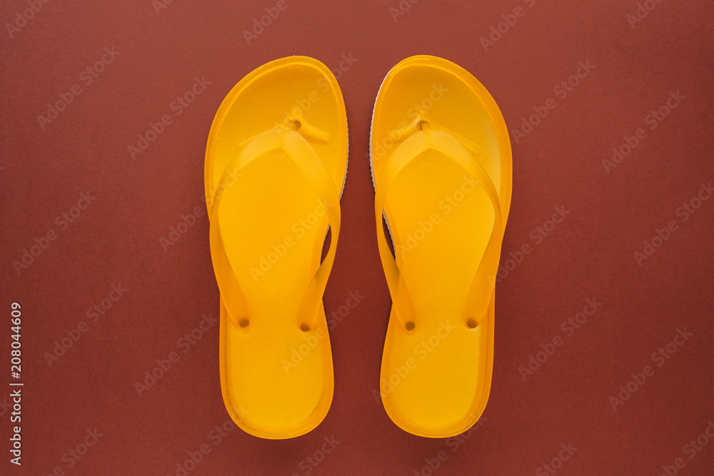Yellow beach flip flops on brown background Yellow beach flip flops on brown background