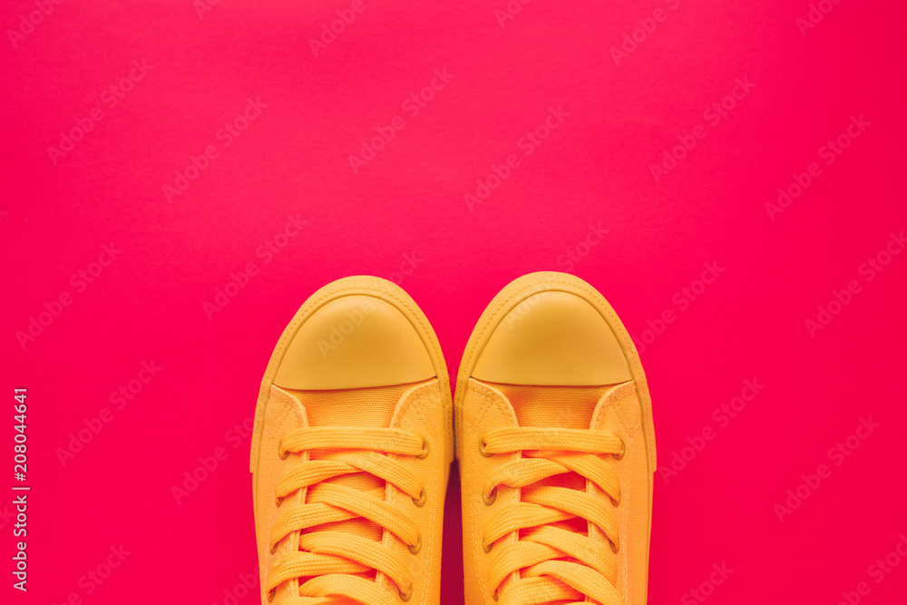 Yellow canvas shoes sneakers on neon pink background Yellow canvas shoes sneakers on neon pink background
