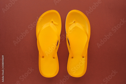 Yellow beach flip flops on brown background