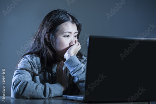 pretty sad Asian Korean student woman looking depressed and worried studying with laptop computer in stress for exam feeling bored and frustrated