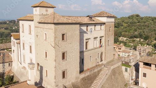 Aerial view of Castelnuovo di Porto castle, near Rome in Italy. The building has a square shape with four towers at the corners. On the facade there is a clock and around the houses of the village. photo