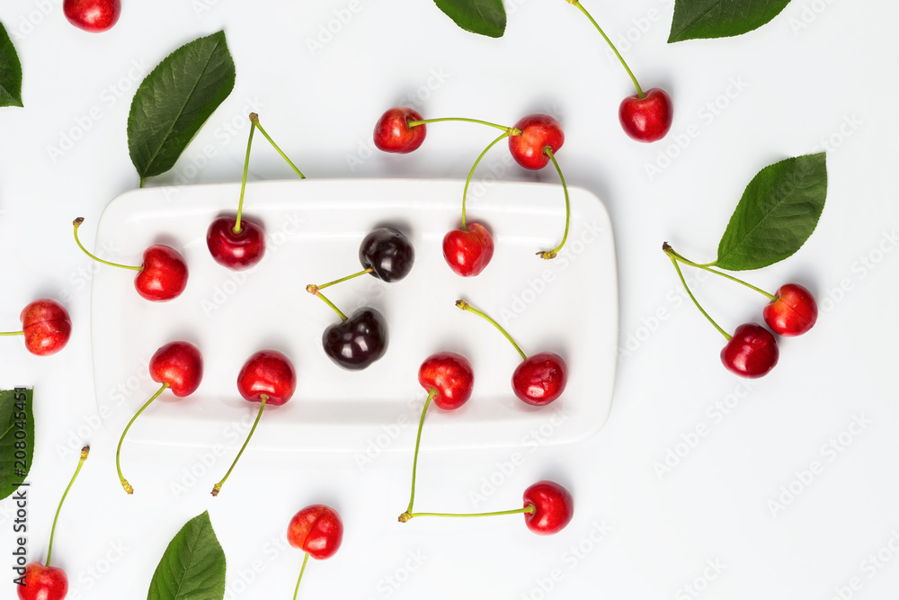 Ripe cherry berries and cherry leaves on white plate isolated top view Ripe cherry berries and cherry leaves on white plate isolated top view