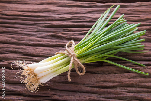 Spring onions also known as salad onions, green onions or scallions on wood background