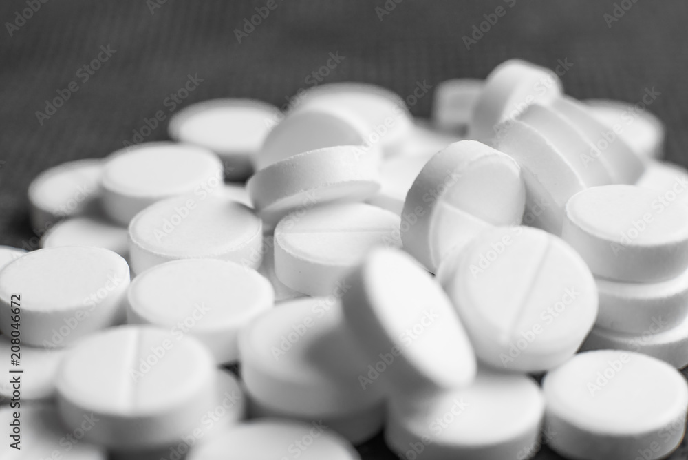 White pills on black background closeup White pills on black background closeup