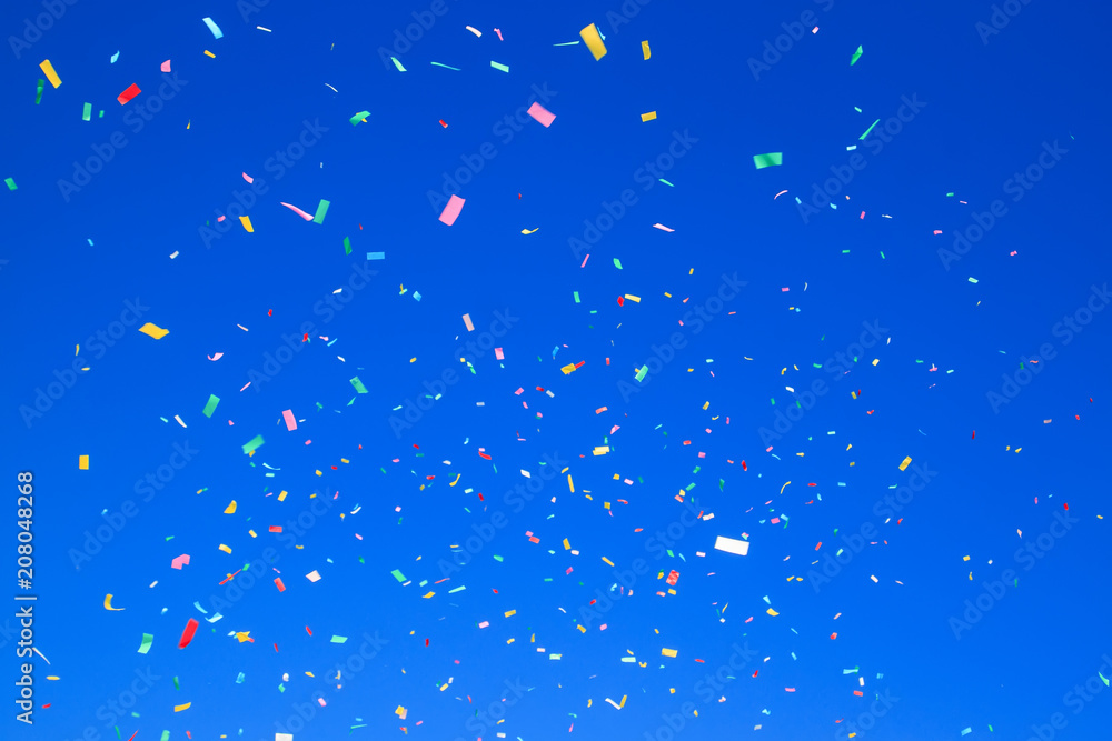 multicolored confetti on clear blue sky background. Concept of holiday backdrop multicolored confetti on clear blue sky background. Concept of holiday backdrop