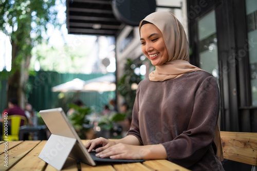 a malay girl at cafe doing work with laptop