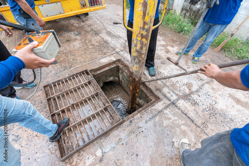 Working for drain cleaning. Problem with the drainage system.
worker with cleaning truck pumps out the dredging drain tunnel cleaning sewage in city street. photo