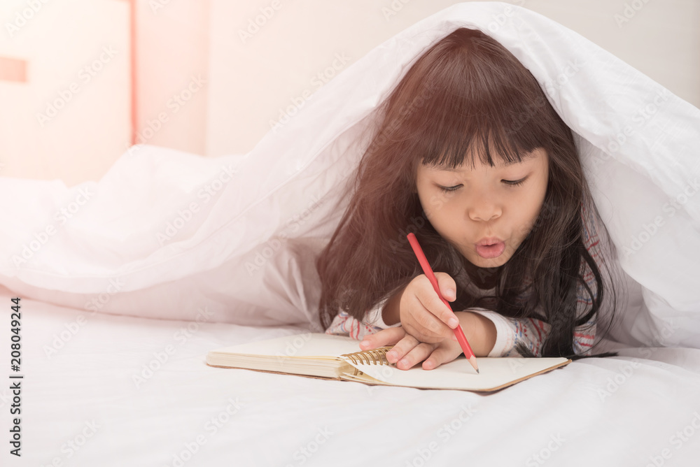 little girl lying on the bed and reading a book little girl lying on the bed and reading a book