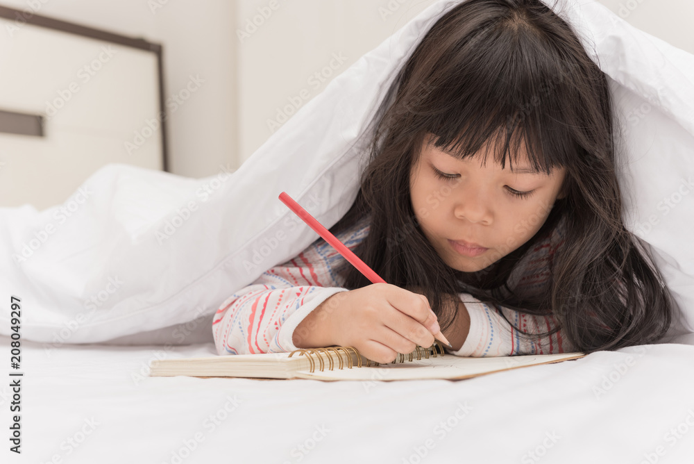 little girl lying on the bed and reading a book little girl lying on the bed and reading a book