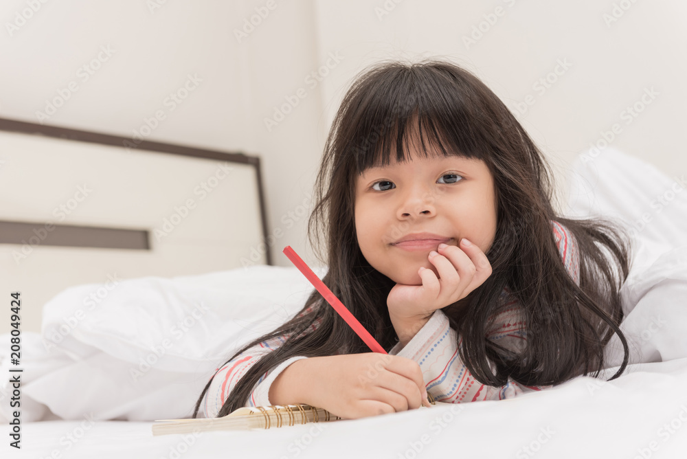 little girl lying on the bed and reading a book little girl lying on the bed and reading a book