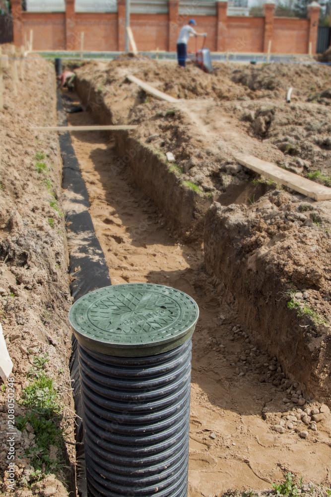 drainage pipes and inspection well for removal of water from a site under construction of the house drainage pipes and inspection well for removal of water from a site under construction of the house