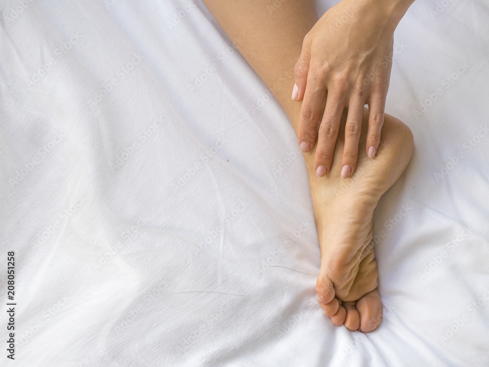 Young woman massaging her foot on the bed., Healthcare concept. Young woman massaging her foot on the bed., Healthcare concept.