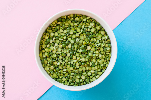 Raw uncooked green peas in a white bowl on duotone background. Top view.
