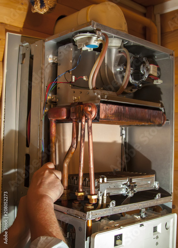 worker installs the heat exchanger after descaling on a workplac photo