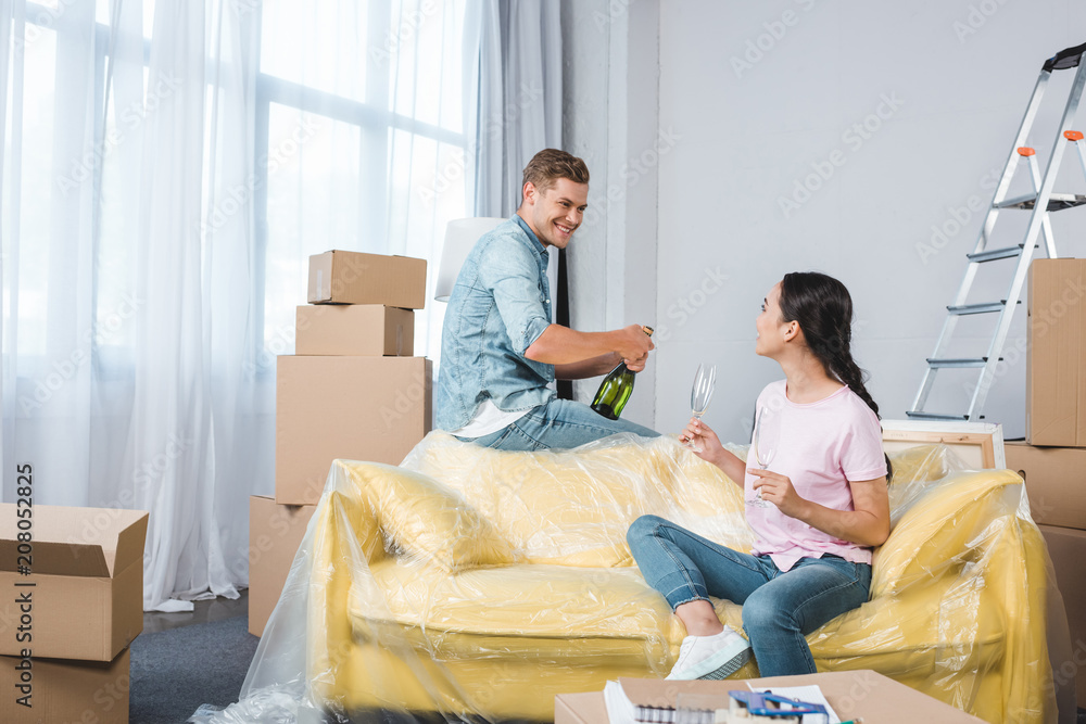 smiling young couple with champagne celebrating after moving into new home smiling young couple with champagne celebrating after moving into new home