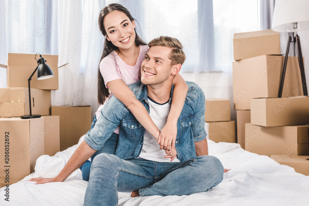 beautiful young couple sitting on bed after moving into new home beautiful young couple sitting on bed after moving into new home