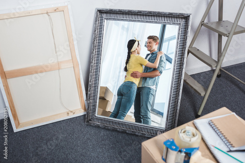 mirror reflection of young couple embracing after moving into new home