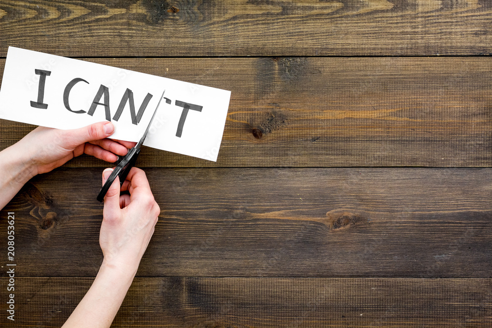 I can concept. Motivate youself, believe in yourself. Hand cut off the letter t of written word I can't by sciccors. Dark wooden background top view copy space I can concept. Motivate youself, believe in yourself. Hand cut off the letter t of written word I can't by sciccors. Dark wooden background top view copy space