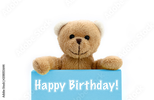 Happy Birthday blue card with brown teddy bear holding with the two hands the note with the message. Photo isolated in a seamless white background. © fewerton