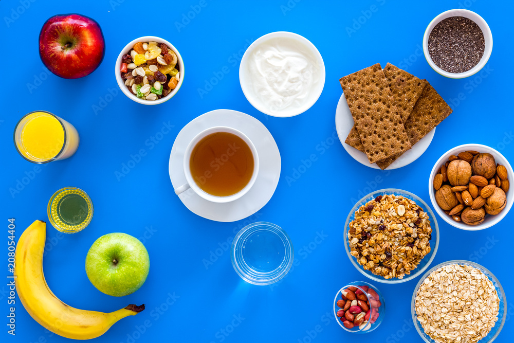 Make a menu for wholesome breakfast. Fruits, oatmeal, yogurt, nuts, crispbreads, chia on blue background top view Make a menu for wholesome breakfast. Fruits, oatmeal, yogurt, nuts, crispbreads, chia on blue background top view