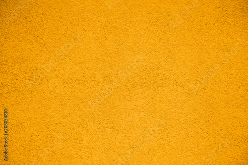 Vivid bright yellow color coarse facade wall as an empty rustic texture background.