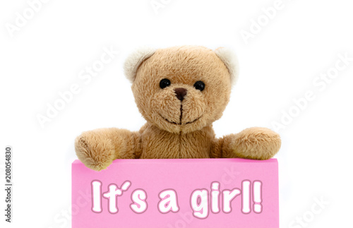 It´s a girl message written on pink card with brown teddy bear holding with the two hands the note with the message. Photo isolated in a seamless white background. Concept for newborn baby girl. © fewerton