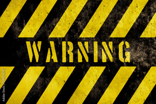 Warning sign text with yellow and dark stripes painted over concrete wall facade texture background. Concept image for caution, danger and hazard.