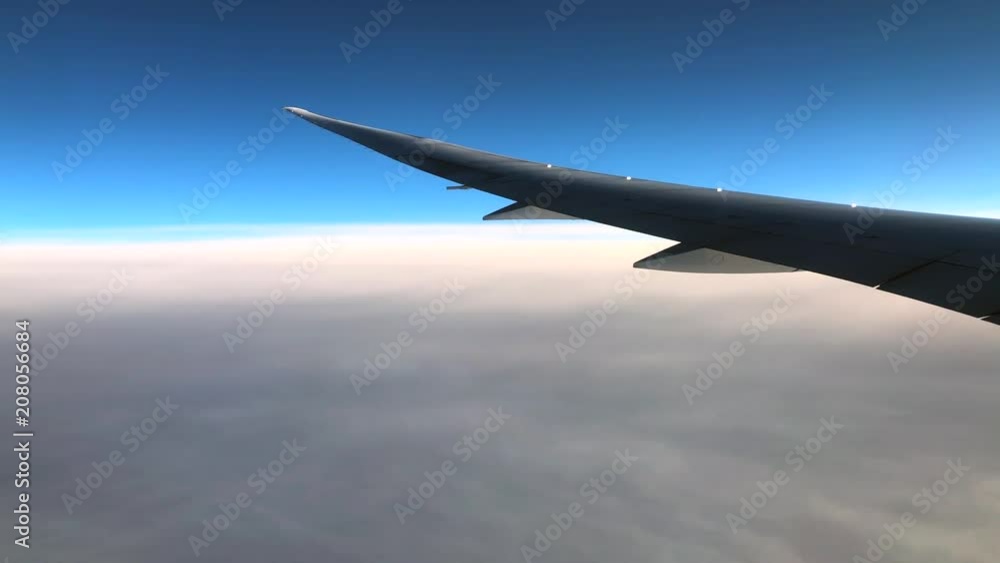 The Wing of Plane and view of clouds through window of an airplane on a sunny day The Wing of Plane and view of clouds through window of an airplane on a sunny day