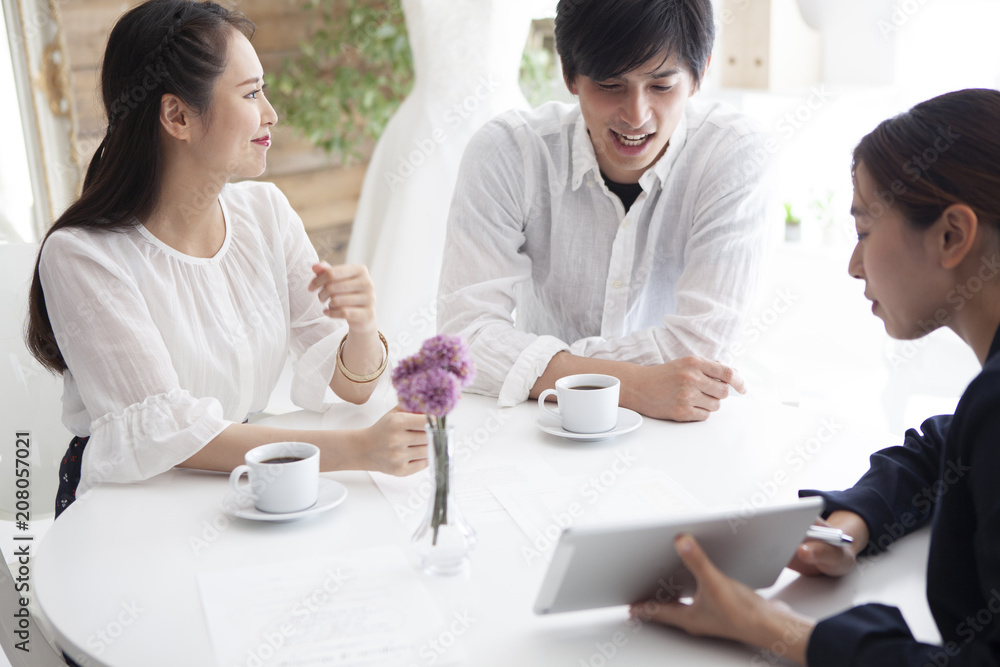 ウエディングプランナーと結婚式の相談をする幸せそうな夫婦 ウエディングプランナーと結婚式の相談をする幸せそうな夫婦