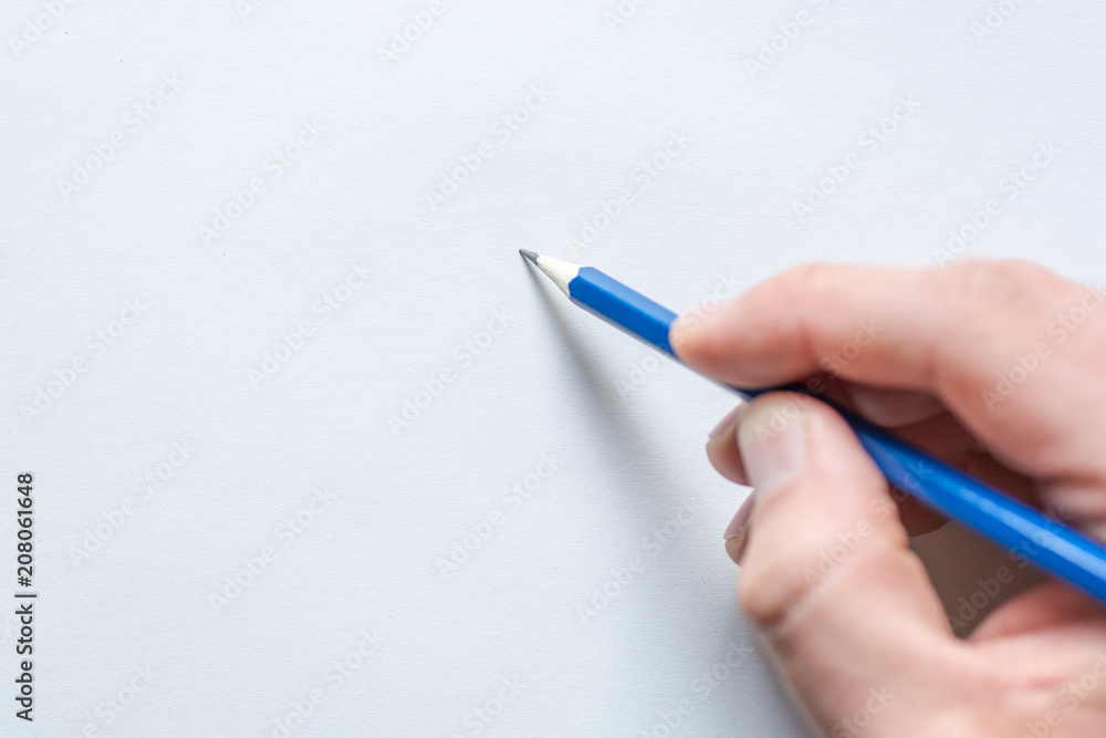 Bleistift in einer Männerhand vor weißem Blatt Papier Bleistift in einer Männerhand vor weißem Blatt Papier
