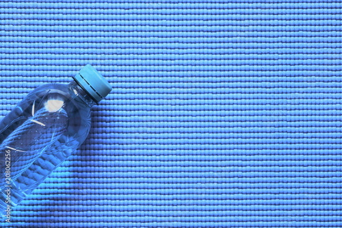Water bottle on light blue background of yoga mat. Concept of healthy lifestile. Flat lay  top view  copy space 