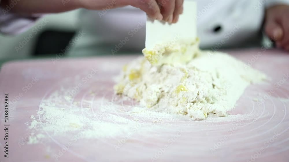 Cake bakery is in process. Young professionalist using wheat flour and an egg yolk for making dough. Modern food devices and technologies