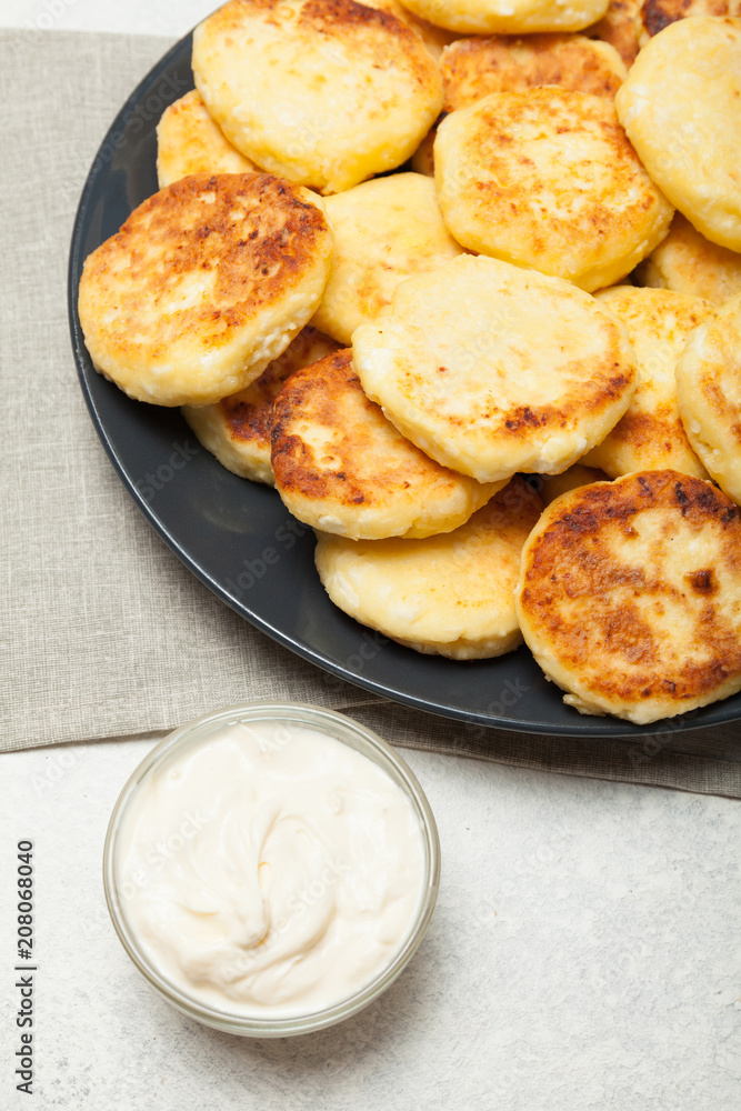 Homemade fried cheese syrniki with sour cream.