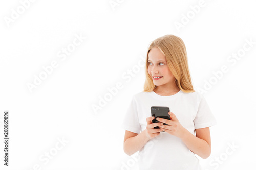 Smiling young blonde girl in casual clothes holding smartphone