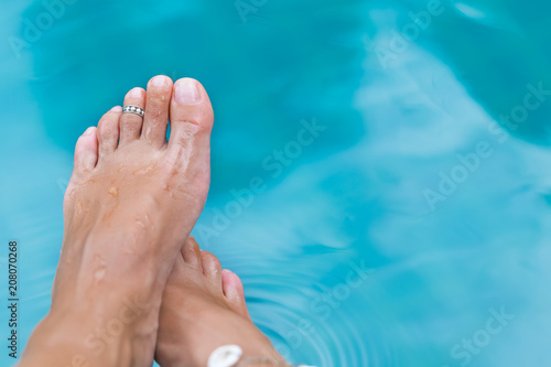 Woman's female legs in blue swimming pool water closeup