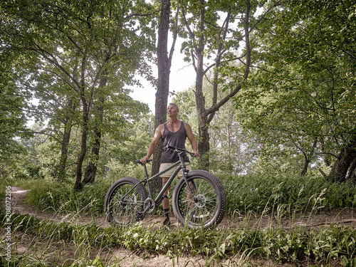 A trained man is riding a fat bike along forest paths.