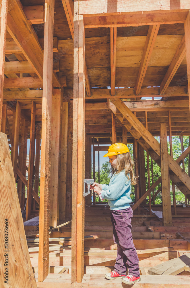 child in a helmet on the construction site of a wooden house child in a helmet on the construction site of a wooden house