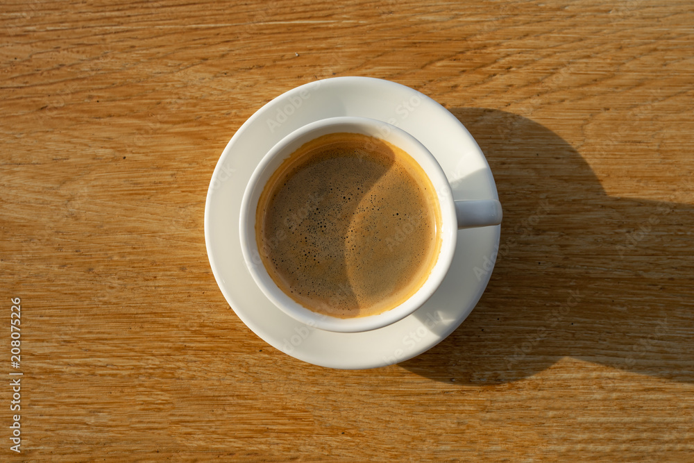 coffee in white cup with sunlight on wood background coffee in white cup with sunlight on wood background