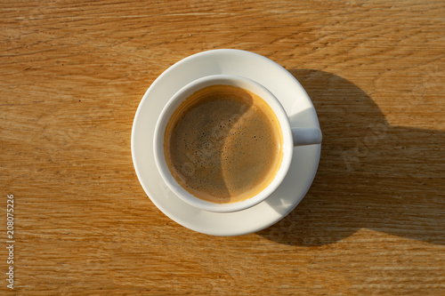 coffee in white cup with sunlight on wood background 