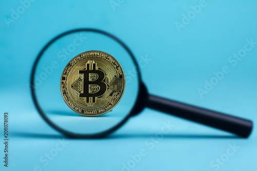 Magnifier glass with golden bitcoin coin