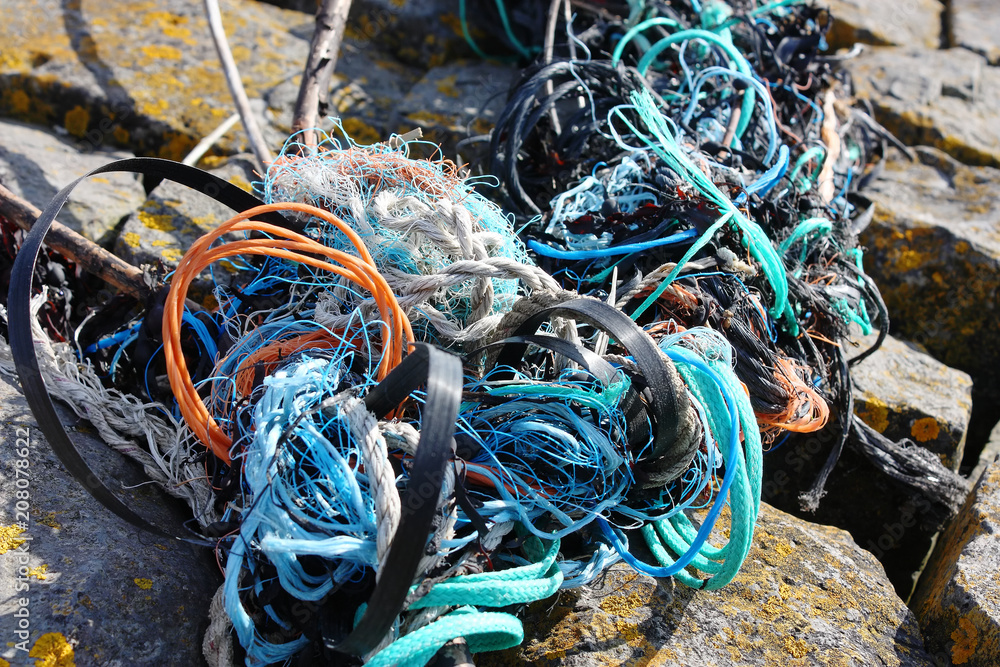 Background of washed ashore tangled orange, blue, green and white plastic lines and ropes. Concept of plastic waste.
