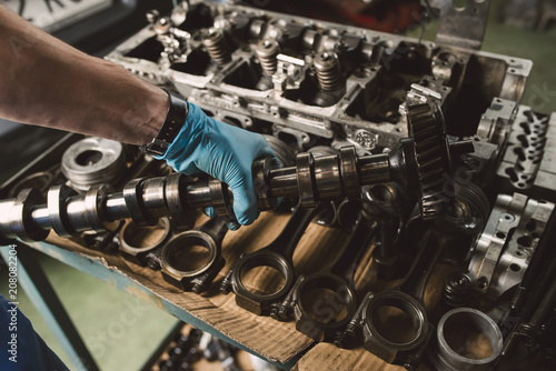 Close-up of mechanic holding the crankshaft of the engine of a car in a workshop photo