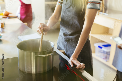 Woman stirring in cooking pot in kitchen