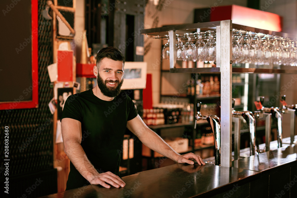 Bartender In Beer Pub. Portrait Of Man At Bar Counter