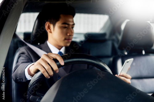Attractive handsome young businessman using mobile smart phone in car © snowing12