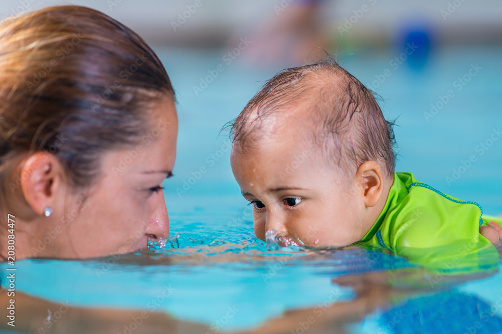 Mother with baby boy in the swimming pool on swimming class