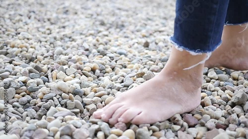 Young woman bare feet walking on pebbles, a useful massage when walking barefooted slow motion