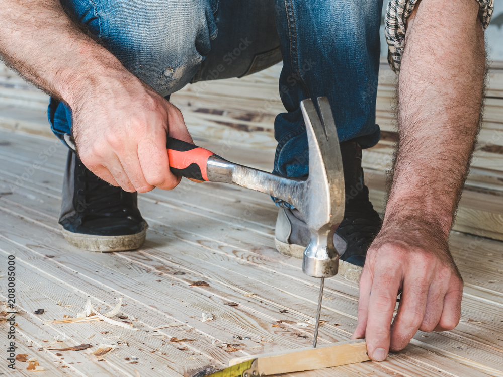 Strong men's hands and tools for working with wood inside the house under construction. Concept of construction and repair