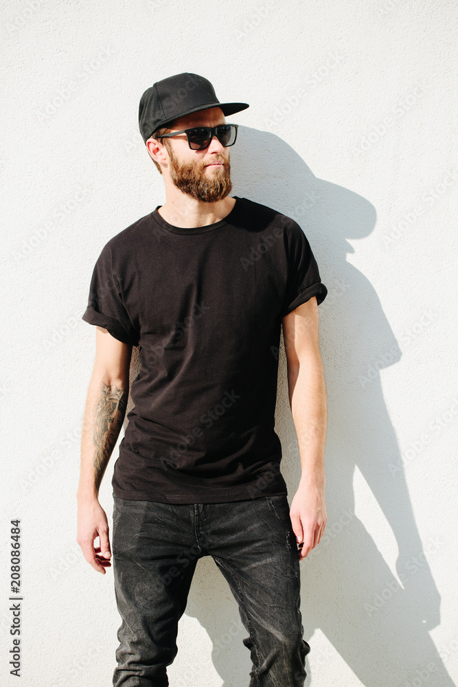 Hipster handsome male model with beard wearing black blank t-shirt with space for your logo or design in casual urban style Hipster handsome male model with beard wearing black blank t-shirt with space for your logo or design in casual urban style